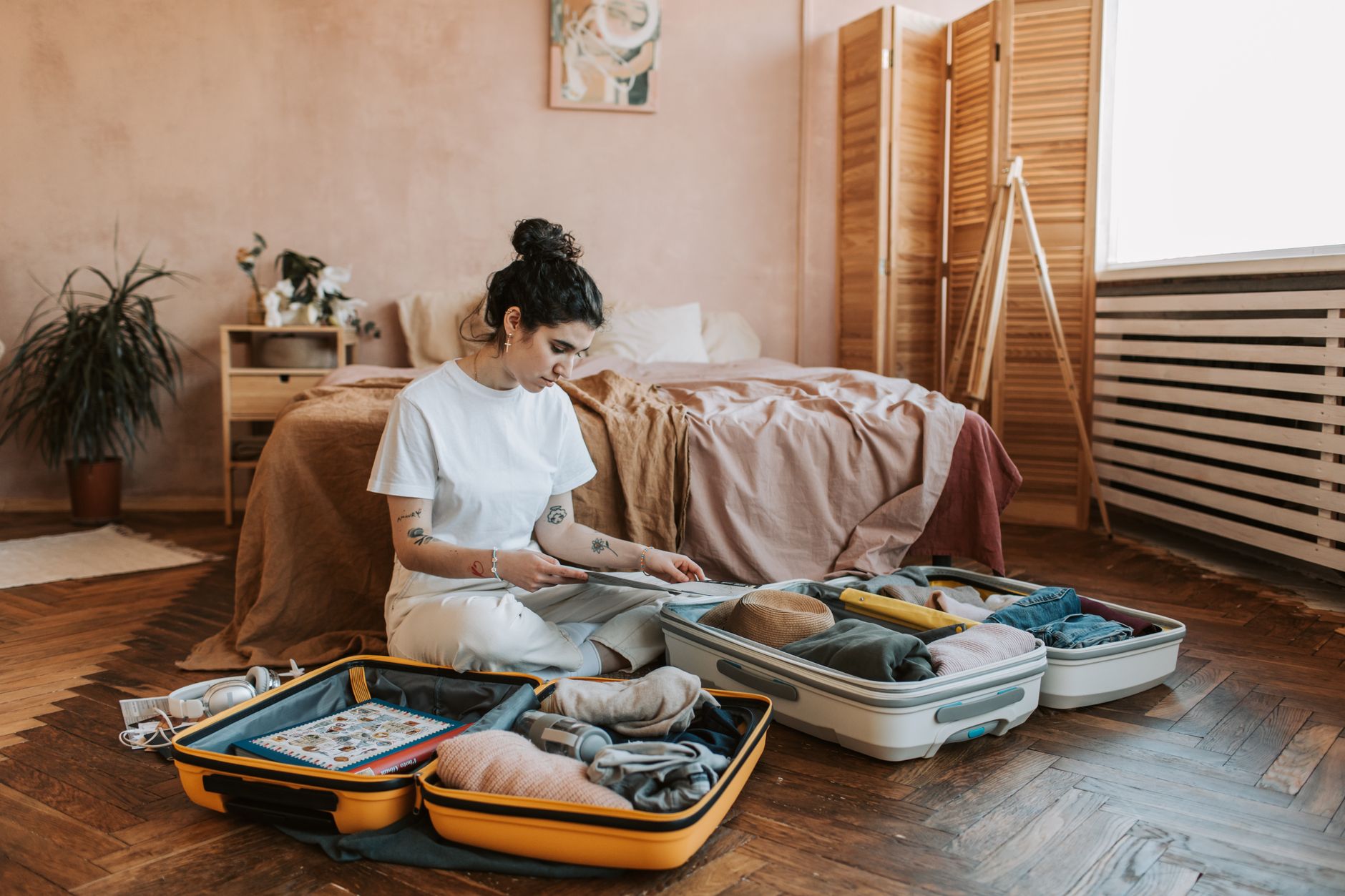 A woman organizes luggage in a stylish bedroom, carrying wanderlust vibes. A woman organizes luggage in a stylish bedroom, carrying wanderlust vibes.