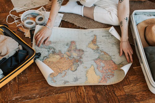 Free Person Opening a Map on the Floor Stock Photo