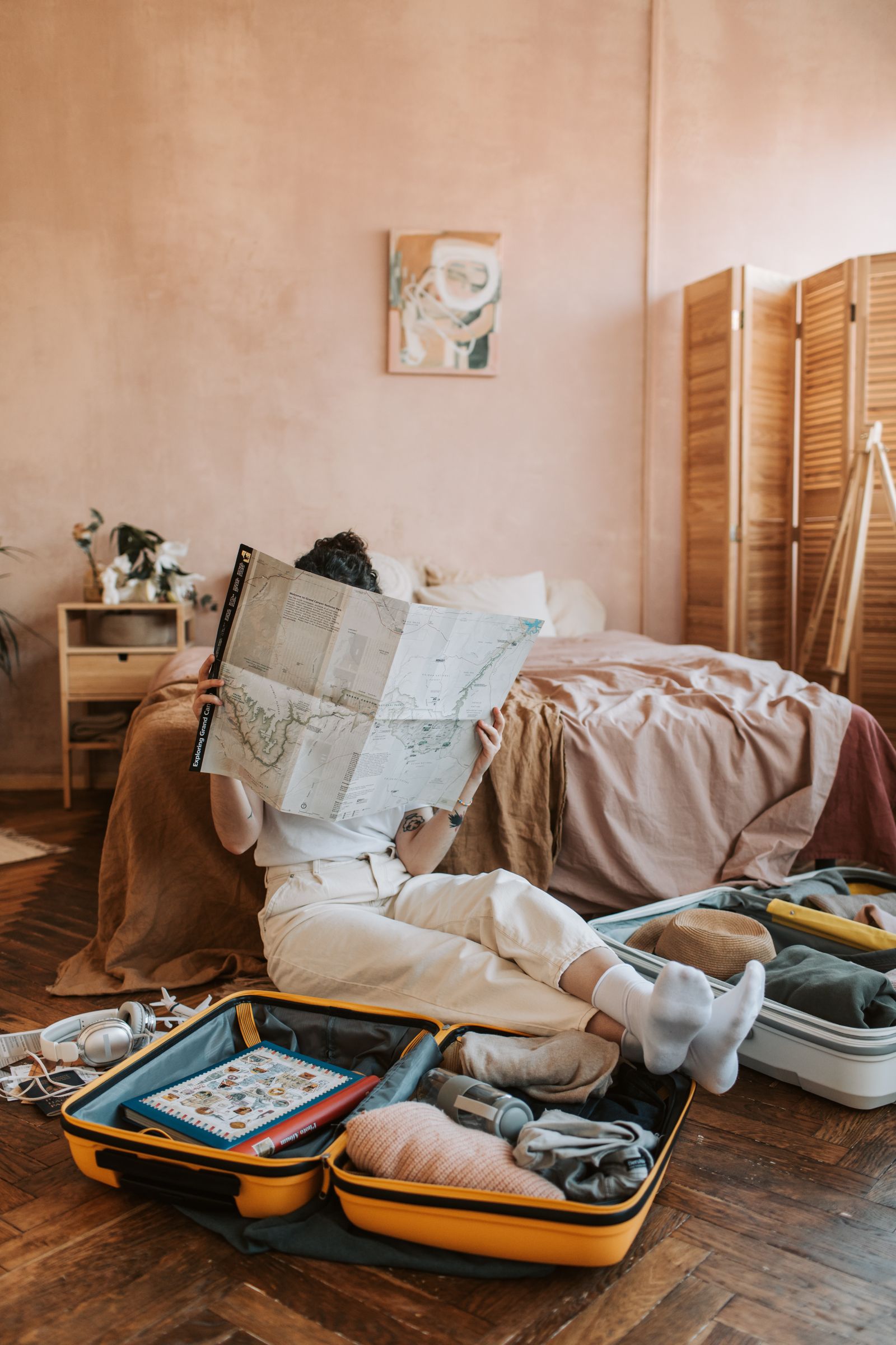 Weekend traveler reviewing a map beside packed luggage and travel essentials