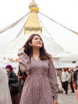 A woman smiles while standing in front of the iconic Boudhanath Stupa in Kathmandu, Nepal.