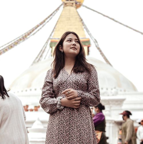 Free A young woman stands in front of the iconic Boudhanath Stupa in Kathmandu, Nepal, looking thoughtful. Stock Photo