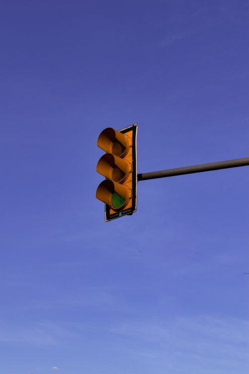 Free A traffic light with green signal against a clear blue sky, ready to go. Stock Photo