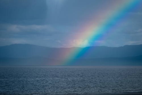 Free A breathtaking view of a rainbow over the ocean against misty mountains in BC, Canada. Stock Photo