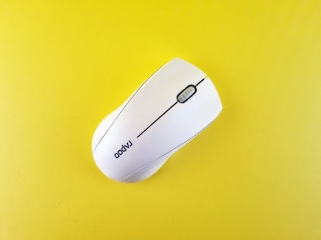 Minimalist white wireless mouse on yellow background, emphasizing modern technology and design.