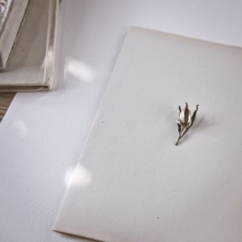 A minimalist still life featuring a dried flower on blank paper, ideal for stationery and art themes.