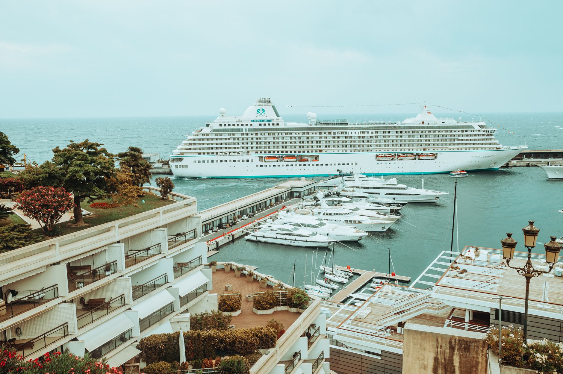 Cruise ship at Monaco Harbor beside yachts and hills, ideal for a post-cruise Riviera resort stay