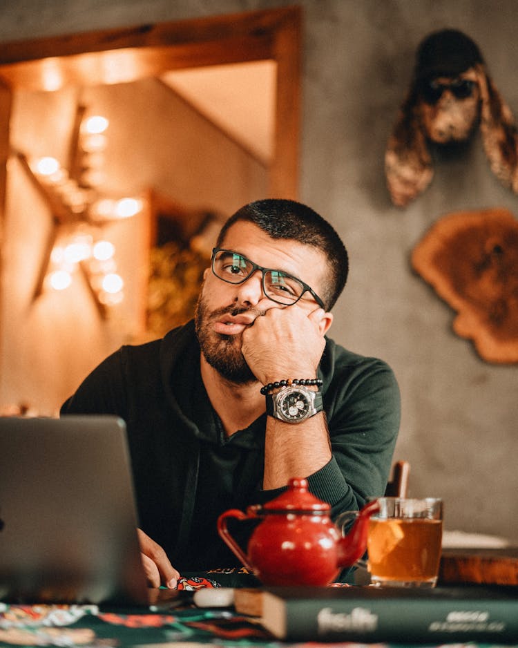 Bored Man At Table With Laptop In Cafe