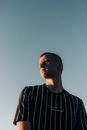 Low-Angle Shot of a Man in a Striped Shirt Looking Away