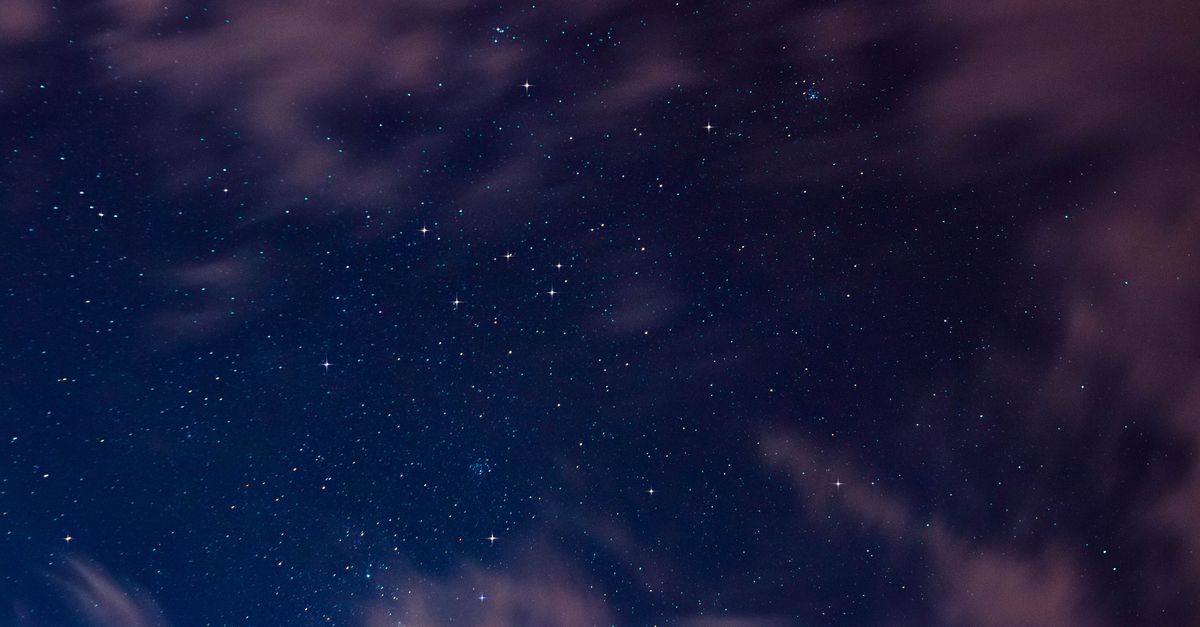 Beautiful starry night sky with scattered clouds and visible constellations.