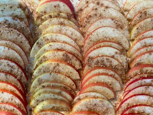 Closeup of delicious homemade pie with rows of slices of apples covered with sugar and cinnamon