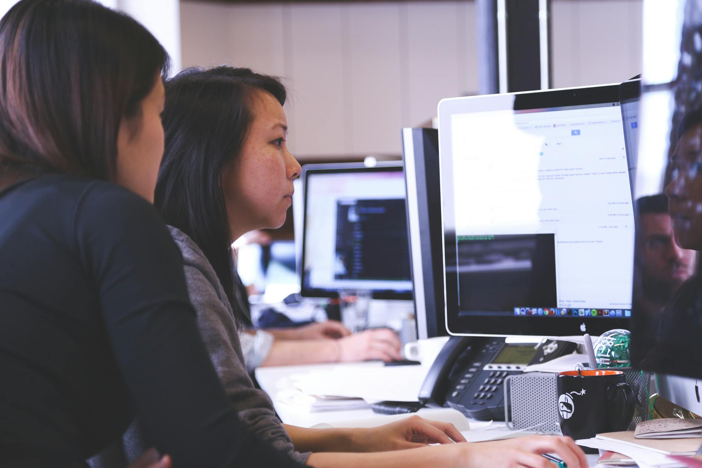 Two women collaborating on a desktop computer