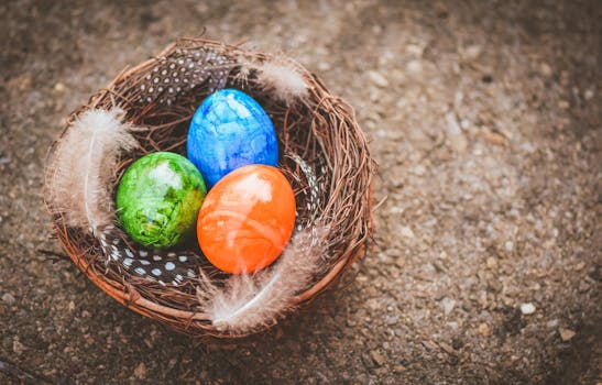 Vibrant colored Easter eggs nestled in a decorative natural twig nest with feathers.