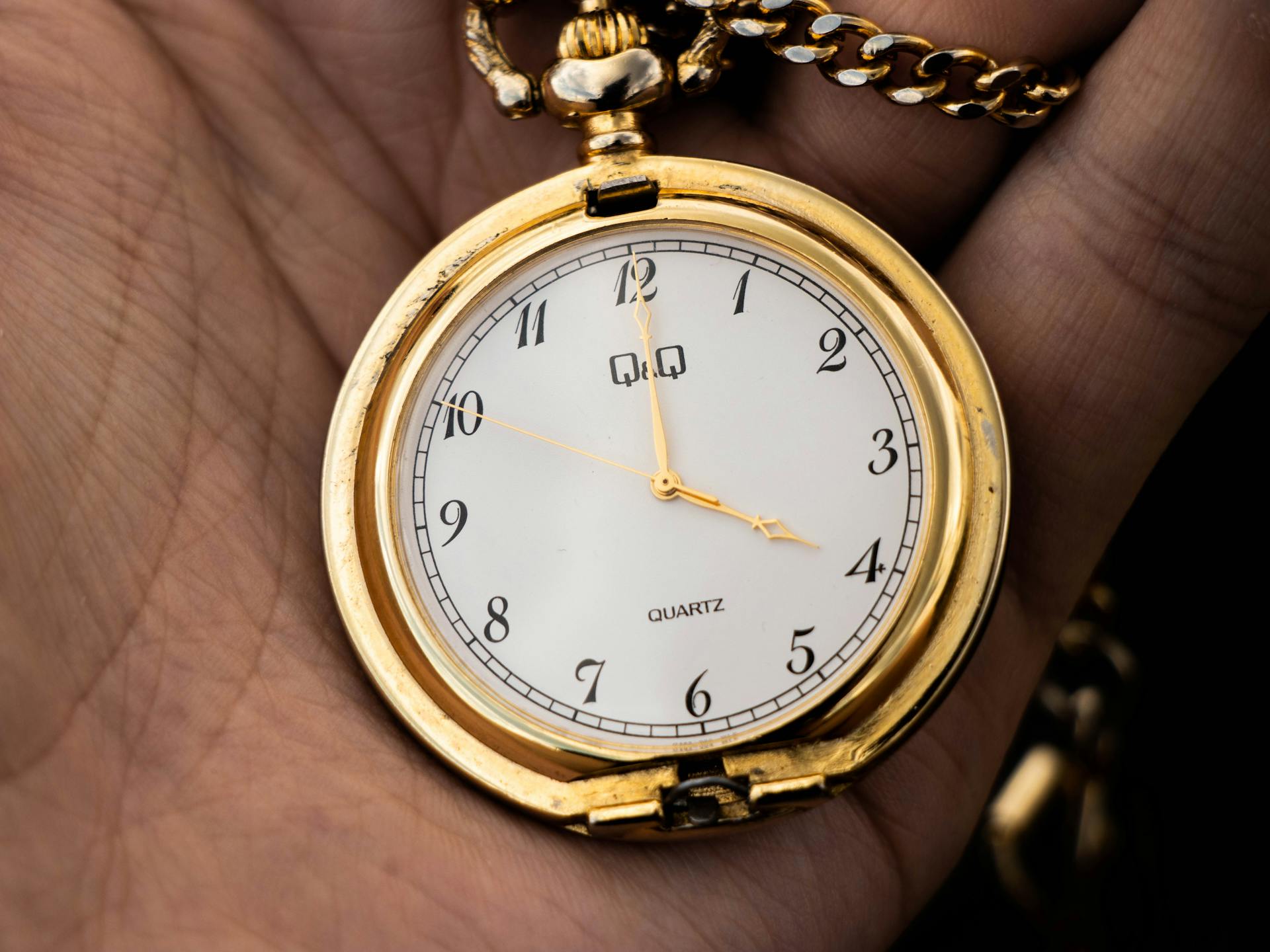 Close-up of a classic gold pocket watch held in hand showing crisp details.