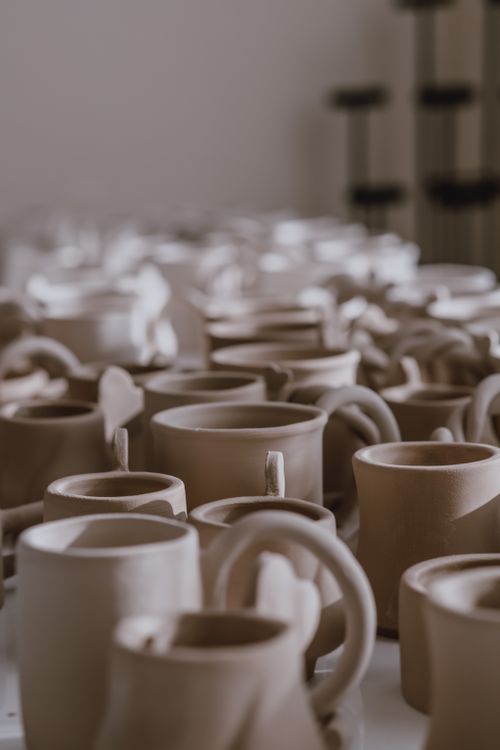 Free A focused view of handcrafted clay mugs in a pottery workshop. Stock Photo