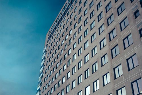 Free From below of huge gray contemporary building with square shaped windows under bright cloudless blue sky Stock Photo
