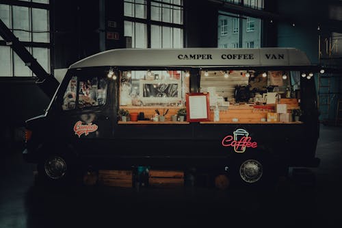 Free Contemporary black coffee van with inscriptions and sparkling signboard in late dark evening Stock Photo