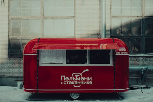 Red food cart offering snacks on a winter day in Saint Petersburg alley.