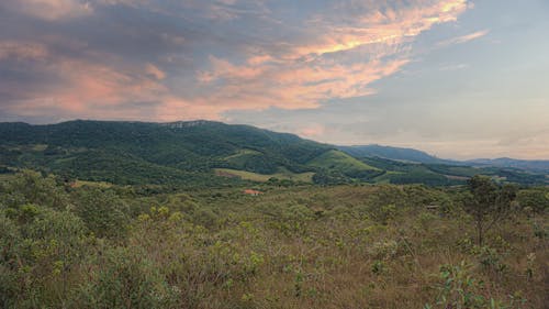 A Green Grass Field Near the Mountain Under the Cloudy Sky