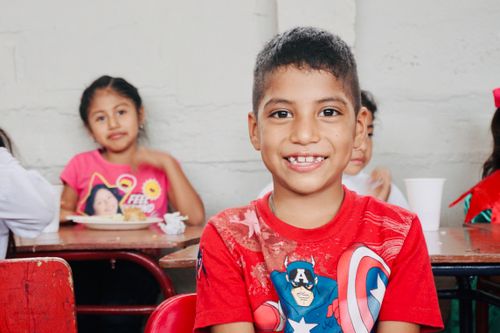 Free Happy child sitting in a classroom, showing joy and innocence. Stock Photo