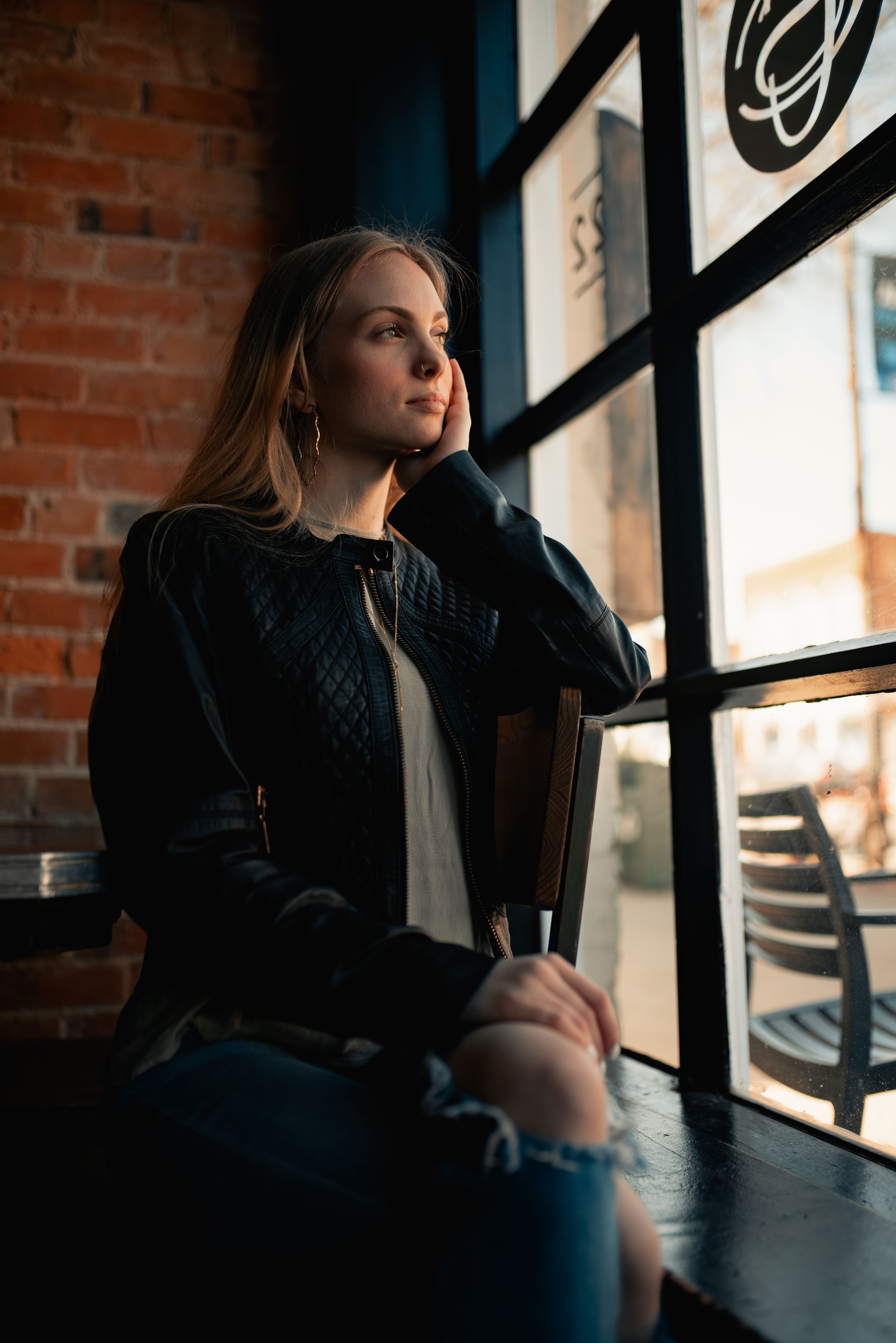 Woman in Black Leather Jacket Sitting on Chair · Free Stock Photo