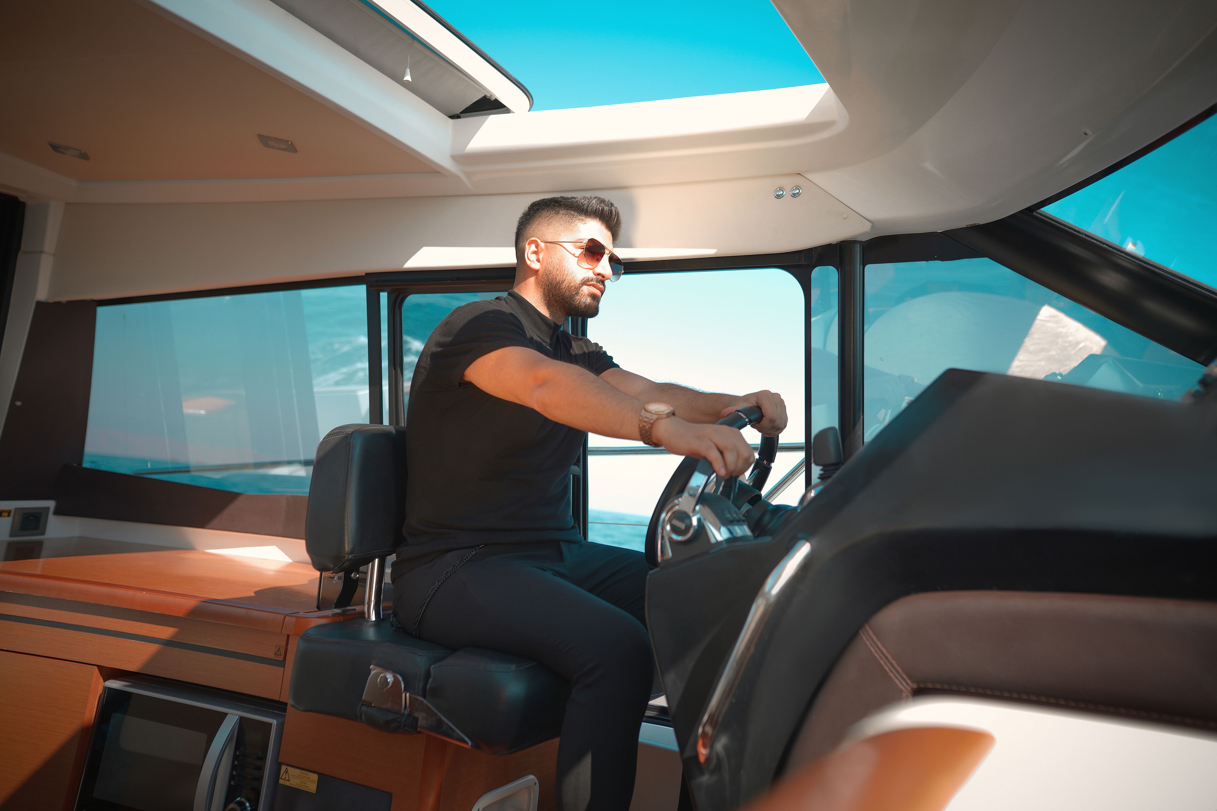 A man confidently steering a luxurious yacht on a bright, sunny day.
