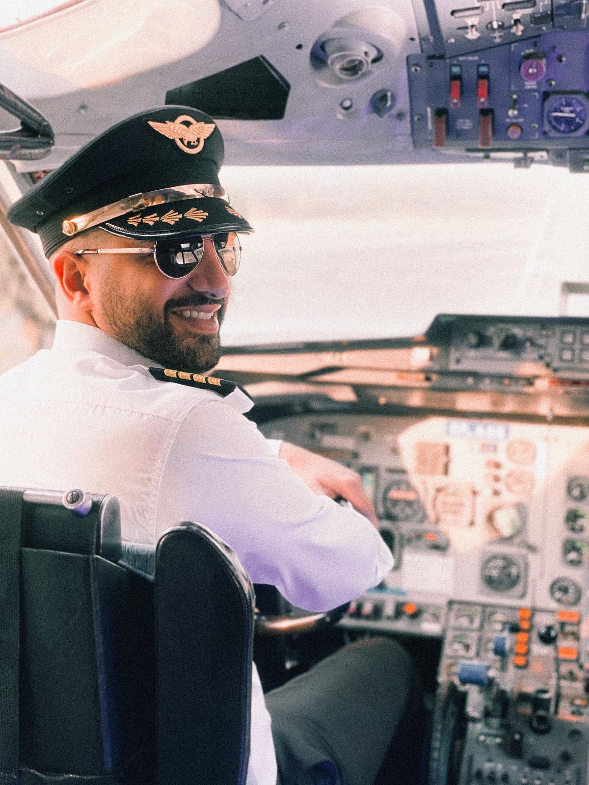 Smiling airline pilot in captain's hat in cockpit — airline pilot salary