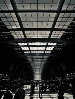 Black and white photo of a crowded modern architectural interior with a vast glass ceiling.