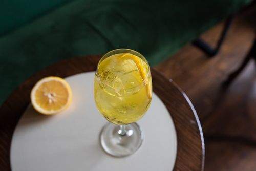 Free Elegant lemon cocktail with ice cubes in a glass on a wooden table, perfect for a refreshing drink idea. Stock Photo