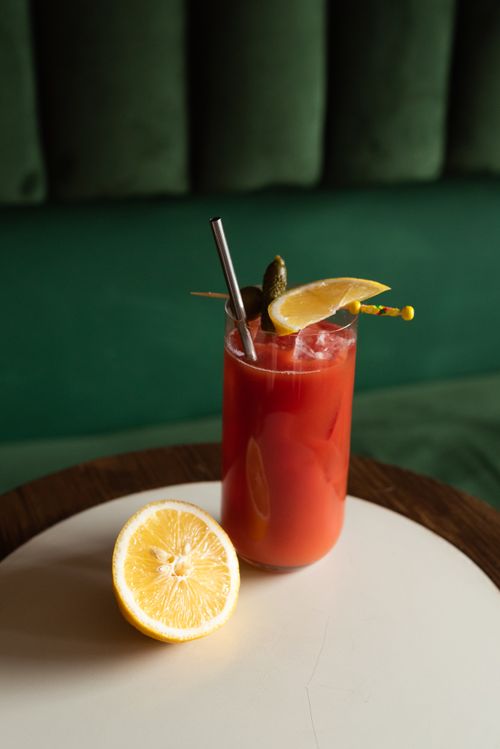 Free Classic Bloody Mary cocktail with lemon, pickles, and metal straw on a table. Stock Photo
