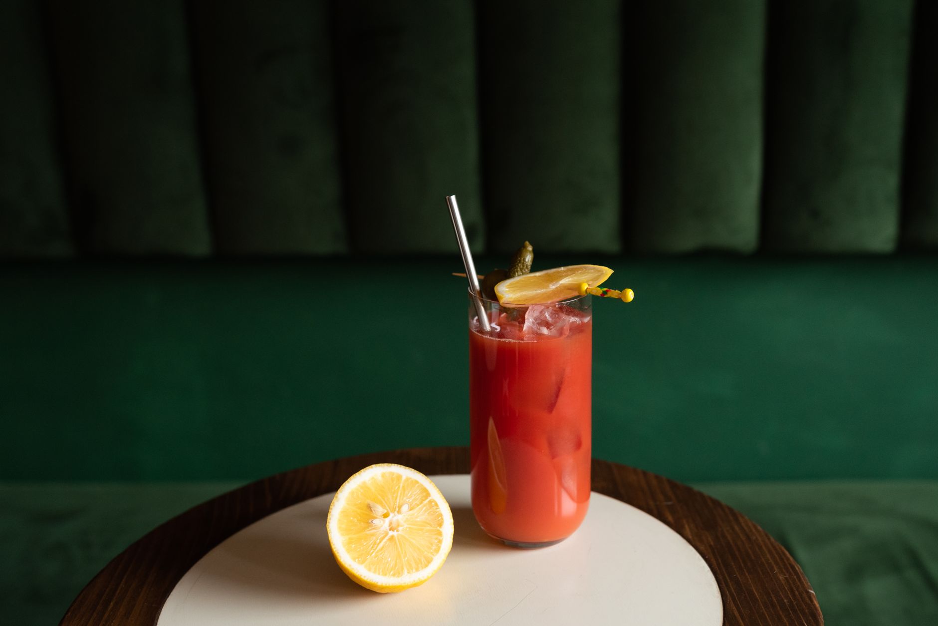 Two glasses of bloody mary garnished with celery and olives on a wooden table