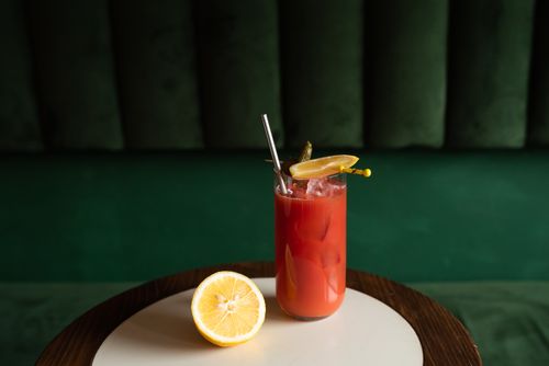 Free A refreshing red cocktail with lemon slices and a pickle garnish on a table. Stock Photo
