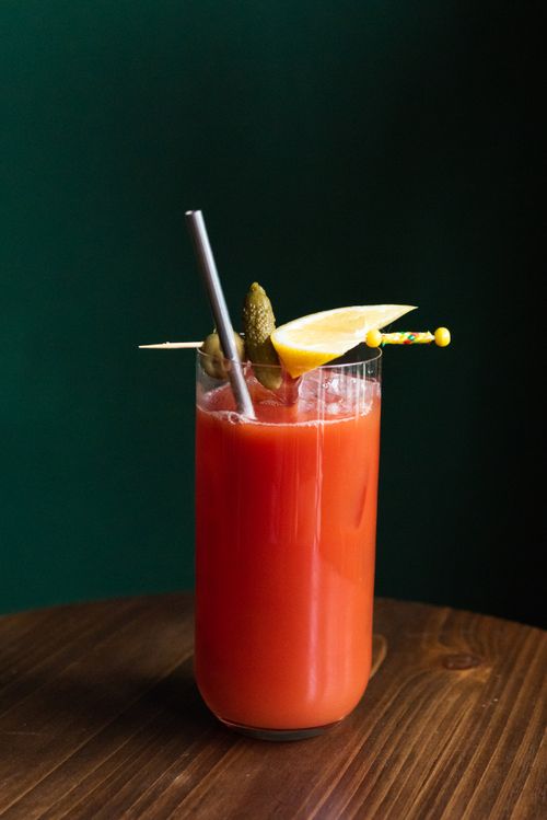 Free Close-up of a delicious tomato cocktail with lemon and pickle garnish on a wooden surface. Stock Photo