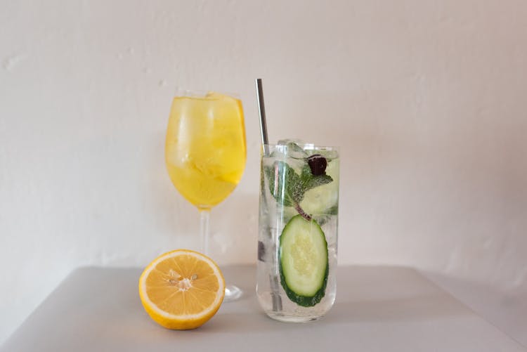 Glasses Filled With Lemon Based Cocktail And Cucumber Water