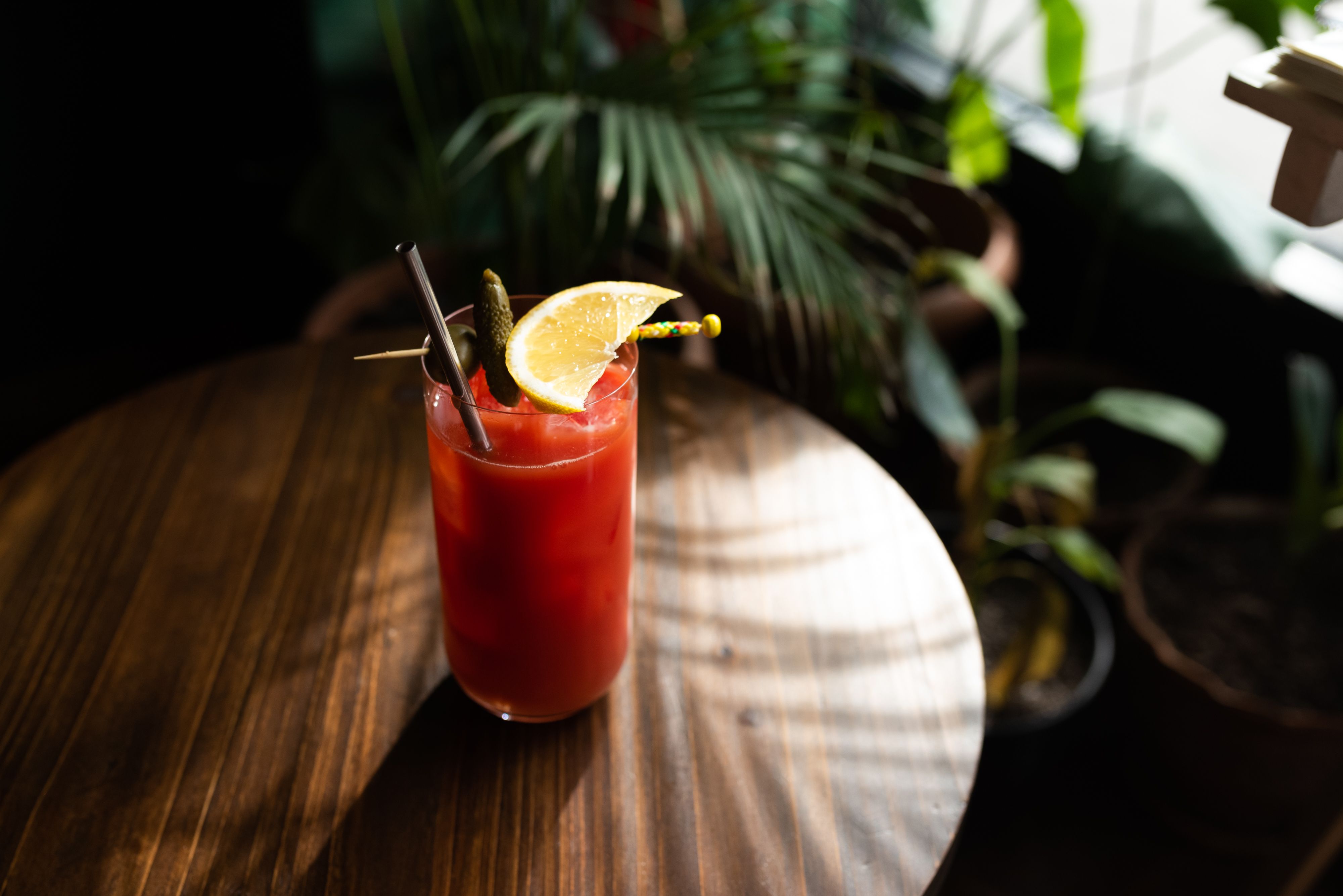Pouring fresh tomato juice into a glass with spices on a wooden board
