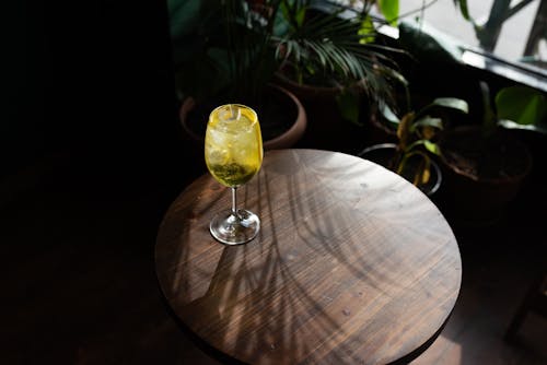 A Wine Glass with Yellow Liquid on a Wooden Table