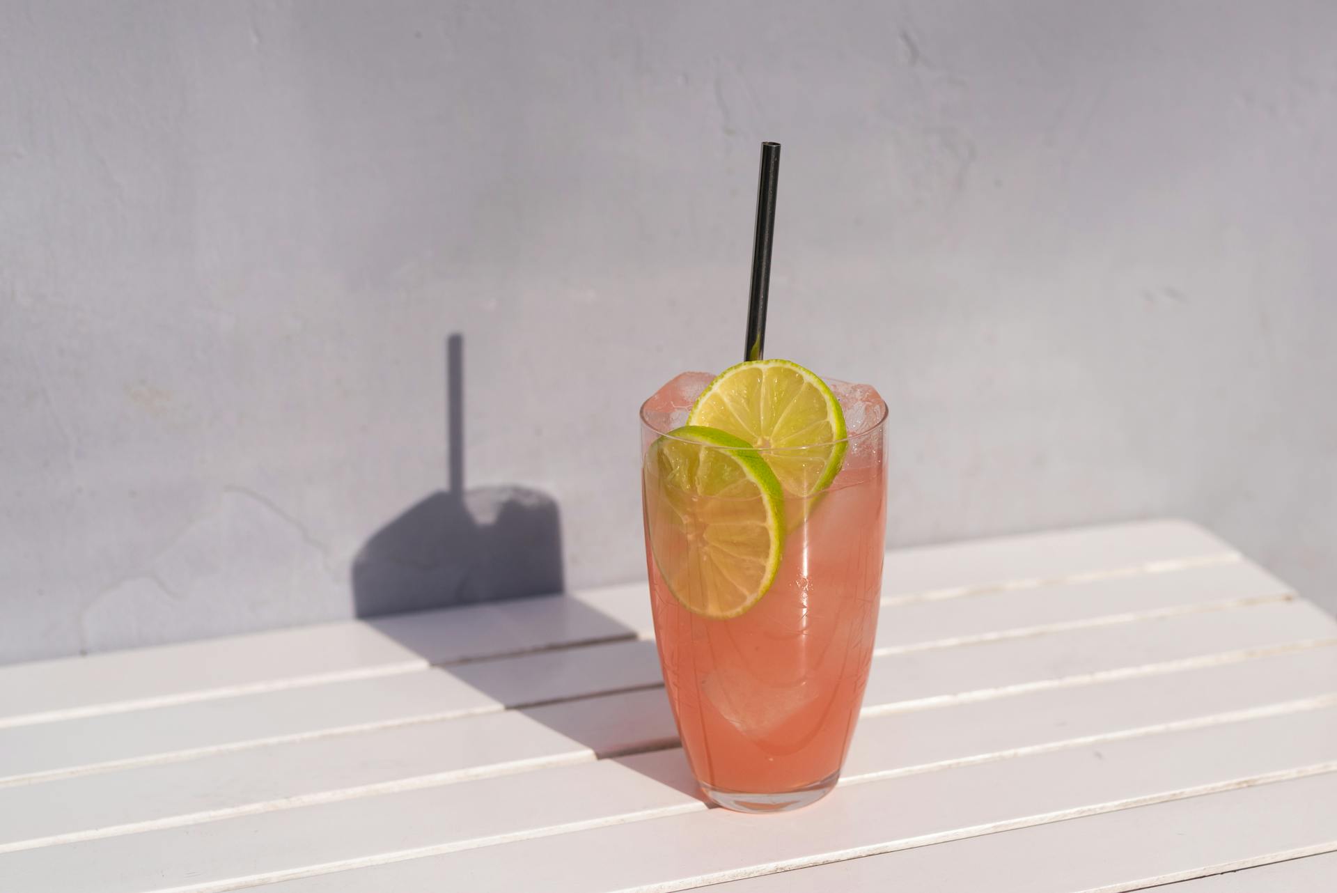 A refreshing pink lemonade garnished with lime slices on a sunny day.