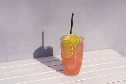 Free A refreshing pink lemonade garnished with lime slices on a sunny day. Stock Photo