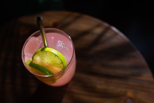 Free Close-up of a pink cocktail with lime slices and ice cubes, perfect for summer refreshment. Stock Photo