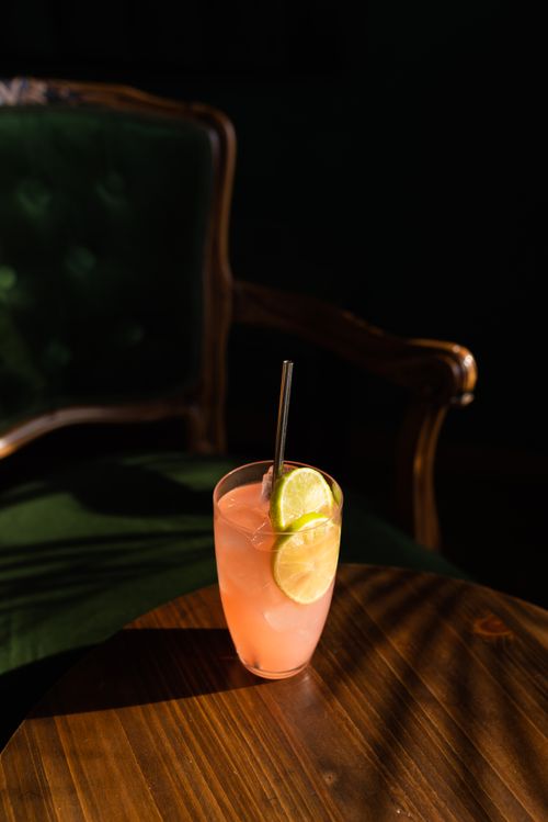 Free A pink cocktail in a glass with lime slices on a wooden table. Stock Photo