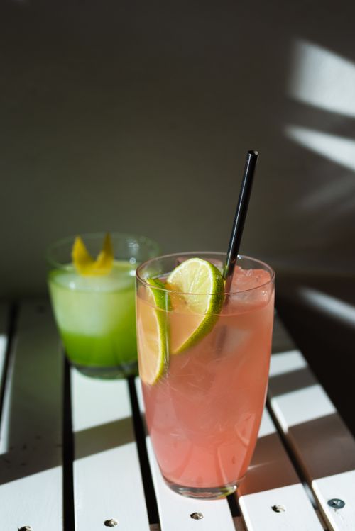 Free A close-up of two colorful cocktails with lime and citrus garnishes, perfect for summer. Stock Photo
