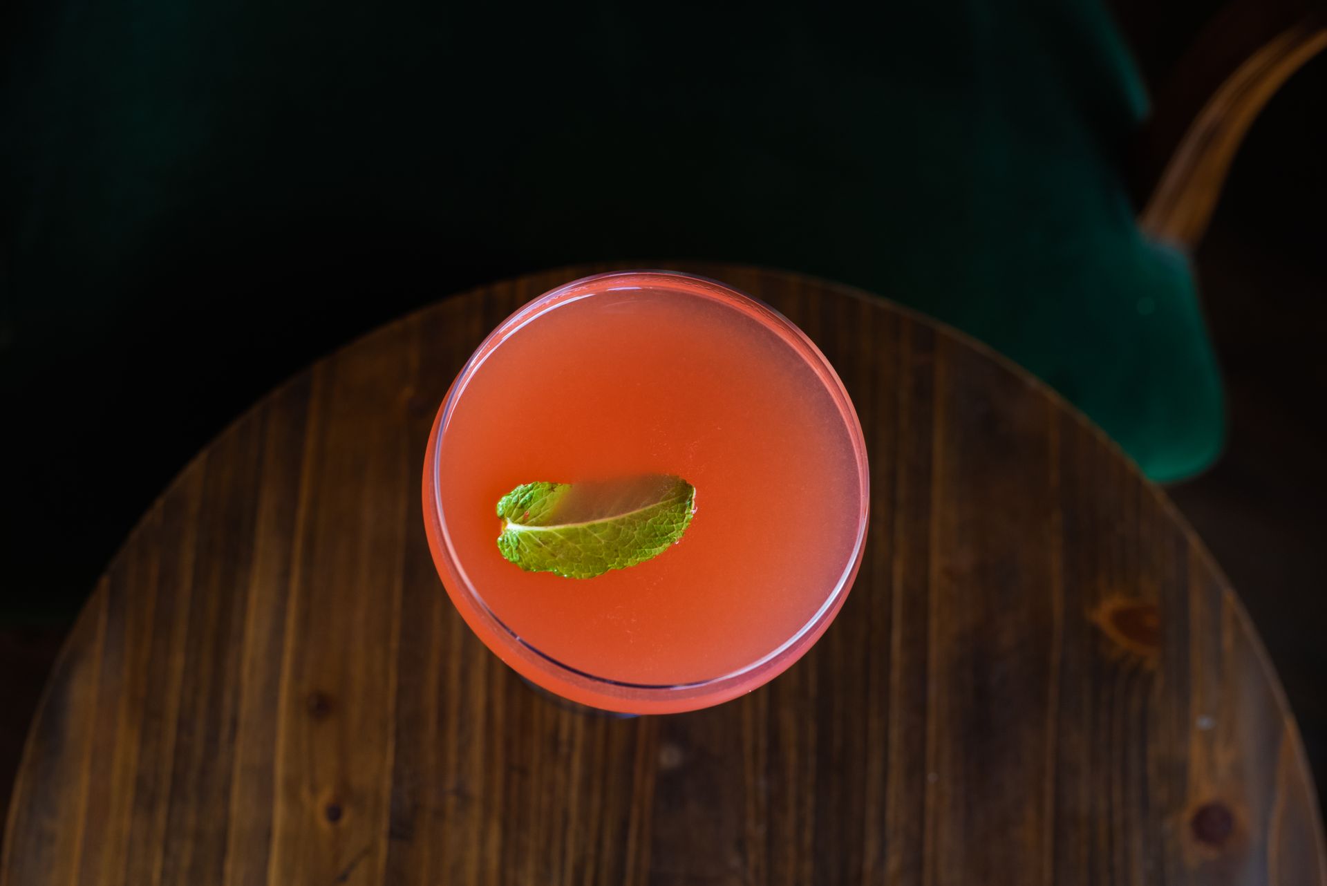 Overhead shot of a mint garnish cocktail on a wooden table.
