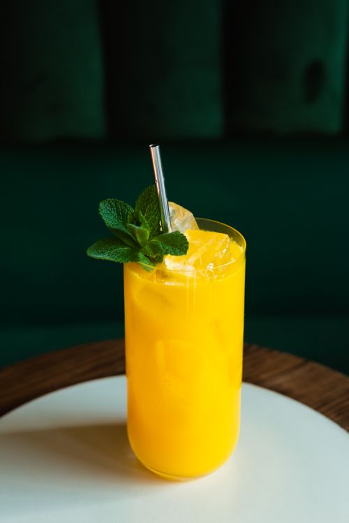 Free Bright citrus cocktail with ice and mint served on a wooden table in a sleek glass. Stock Photo