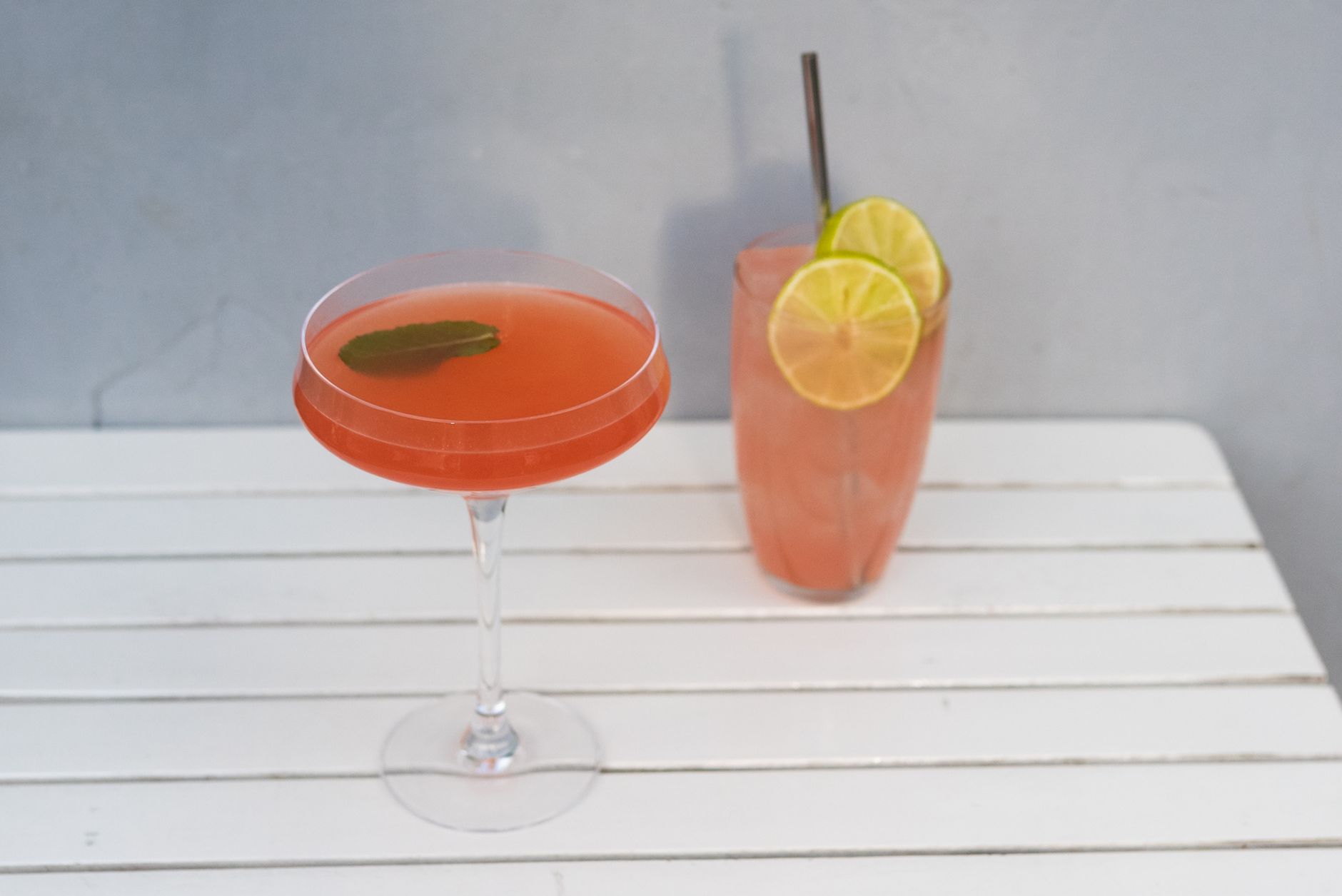 Bartender pouring a bitter cocktail with garnishes on a wooden bar