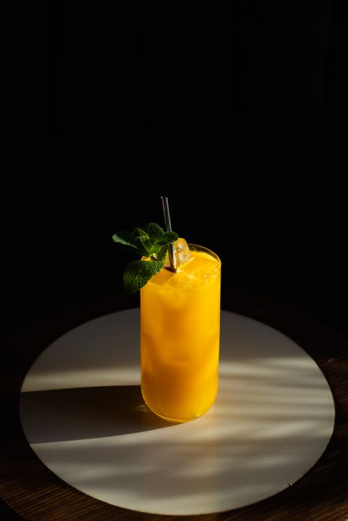 Free A vibrant orange cocktail with mint garnish in a sleek glass on a table. Stock Photo