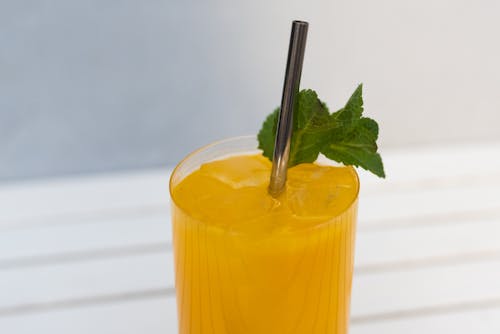 Close-Up Shot of Yellow Juice with Green Mint Leaves