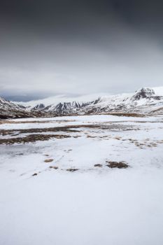 A stunning winter landscape of snow-capped mountains in Búðardalur, Iceland, showcasing a serene and frosty scenery.