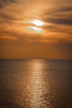 Capture of a stunning sunset over the sea in İstanbul with warm, golden hues.