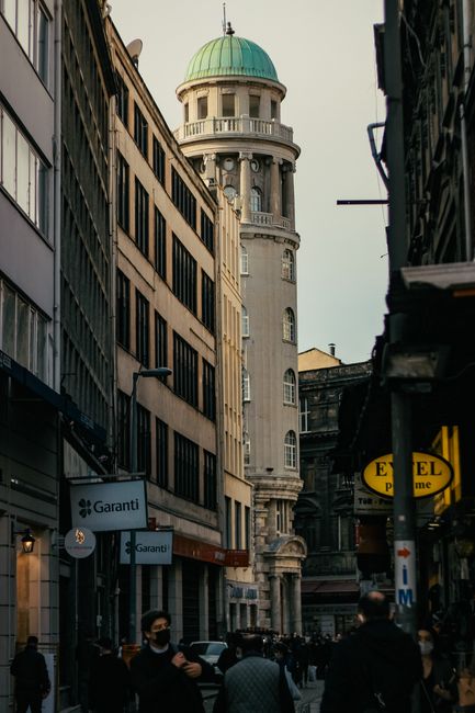 A bustling urban street scene in Istanbul featuring a historic tower and busy pedestrians.