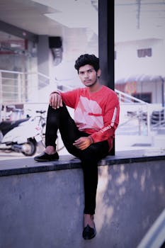 一个时尚男人穿着红色衬衫，在城市中自信地摆姿势