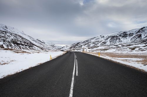 Free A picturesque highway in Búðardalur, Iceland with snow-capped mountains and a moody sky. Stock Photo